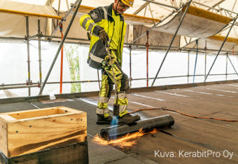 Mies tekee tulitöitä bitumikattoa asentaessaan.