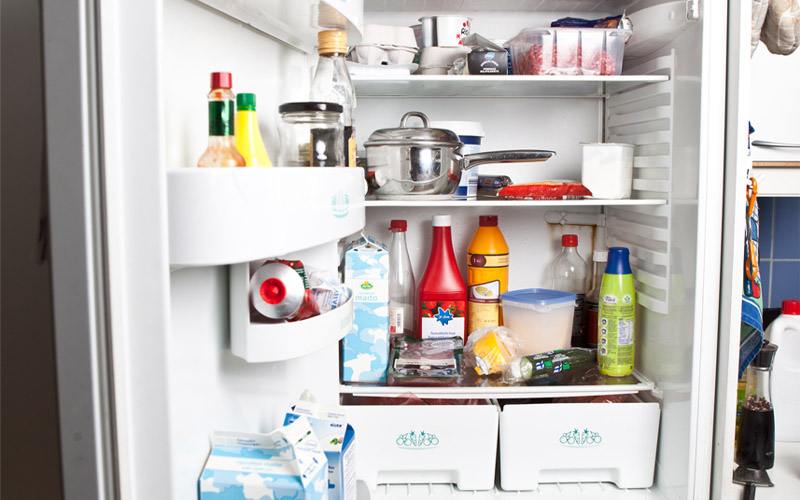 Jääkaapin ovi auki ja jääkaapin sisällä ruokaa ja maitopurkkeja.