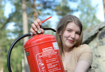 Hymyilevä nainen pitelee käsisammutinta.