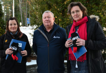 Nainen, mies ja nainen seisovat ulkona tyytyväinen ilme kasvoillaan..