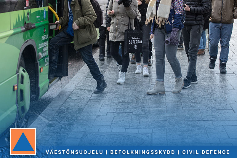 Ihmisiä nousemassa bussiin ja heillä on selässä reppua ja kädessä kassia.