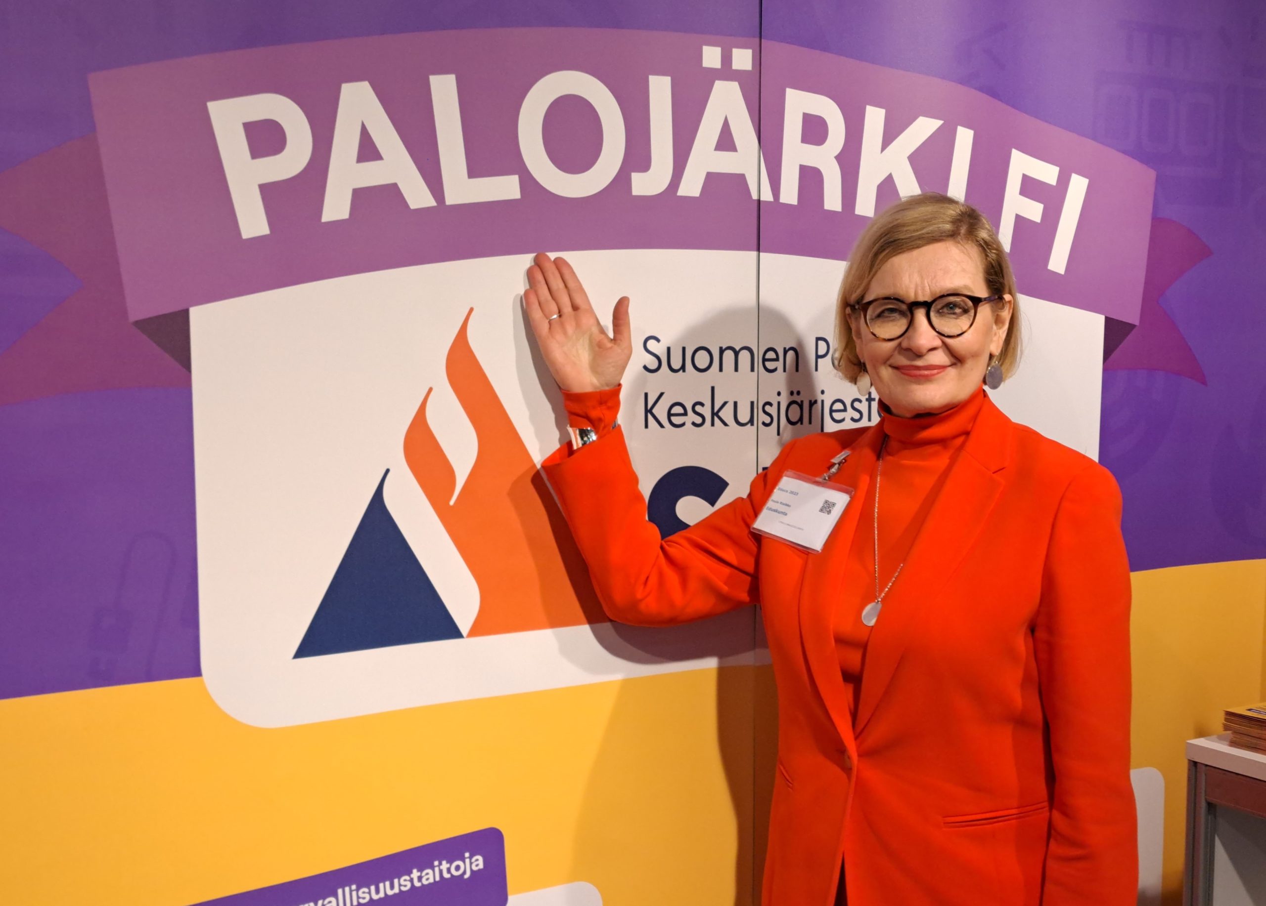 Paula Risikko osoittaa kädellään messuosaston seinällä olevaa Palojärki.fi-nimeä.