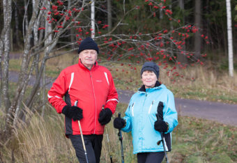 Eläkeikäiset mies ja nainen sauvakävelyllä.
