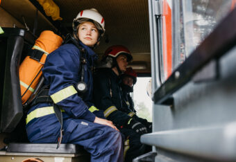 Palokuntanuori istuu varusteet päällä paloautossa.