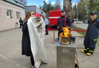 Nainen harjoittelee kattilassa olevan palon sammuttamista sammutuspeitteellä Päivä Paloasemalla -tapahtumassa.