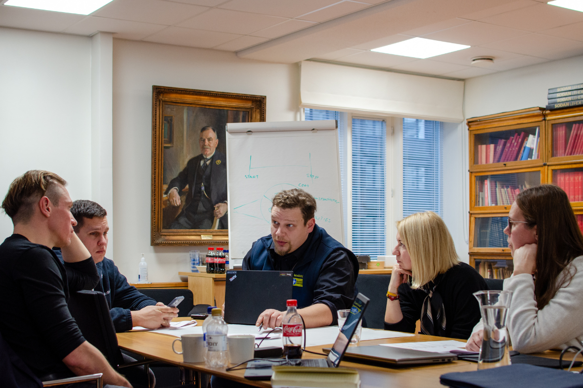 Ihmisiä keskustelemassa toimistossa pöydän ääressä.