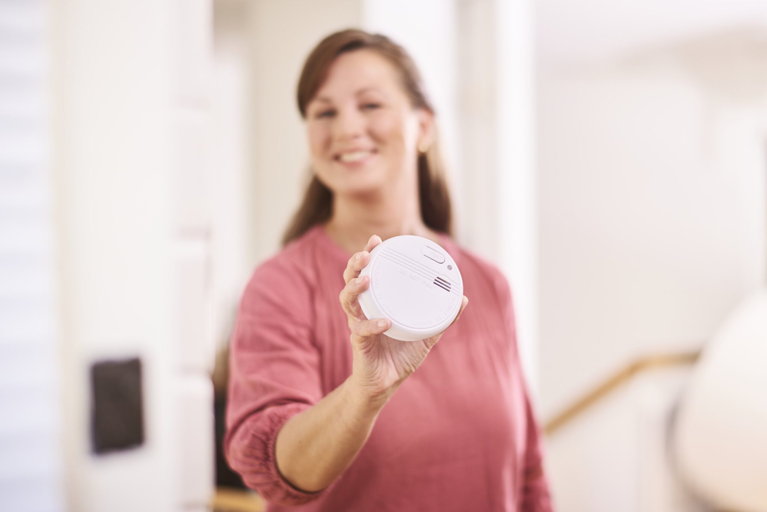 En kvinna håller en brandvarnare i sin hand.