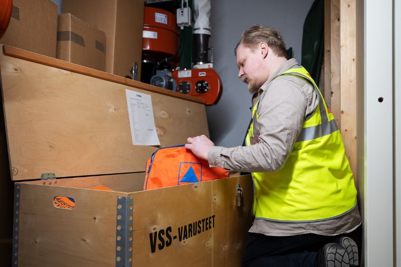Mies tutkii väestönsuojan varustelaatikon sisältöä.