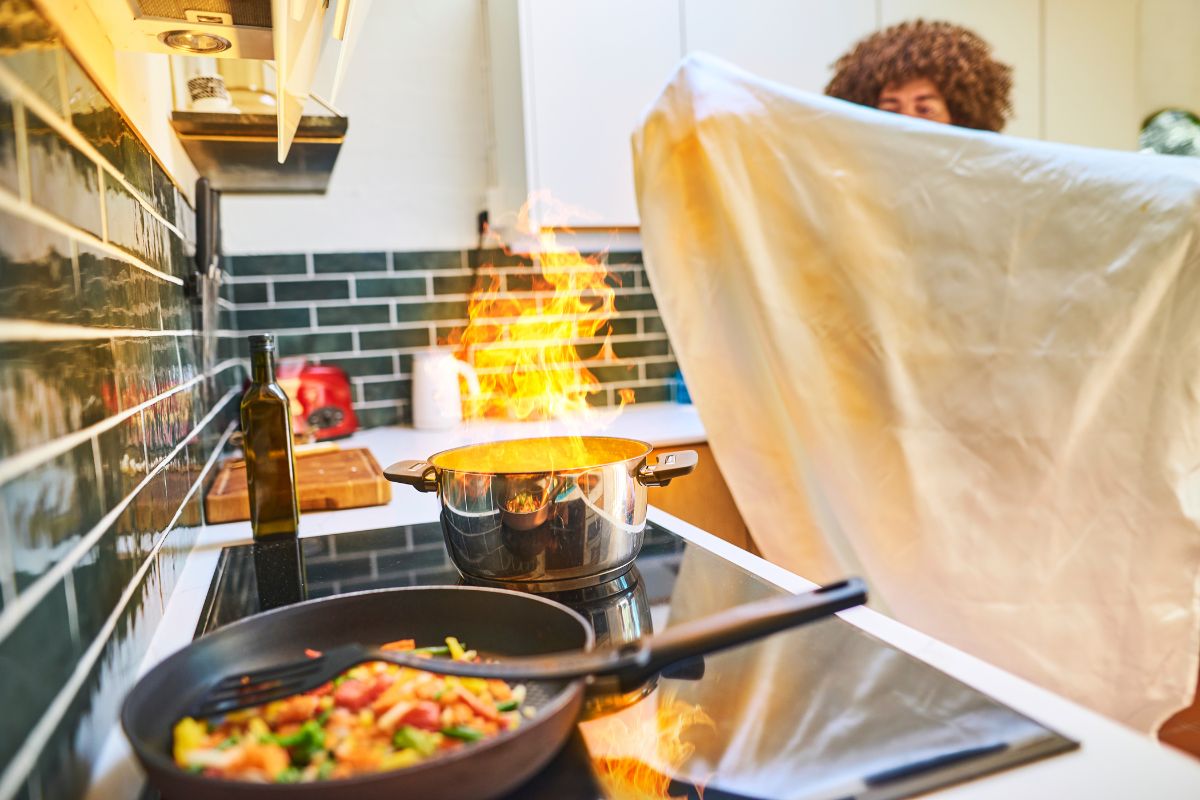 Mies sammuttaa rasvapaloa sammutuspeitteellä.