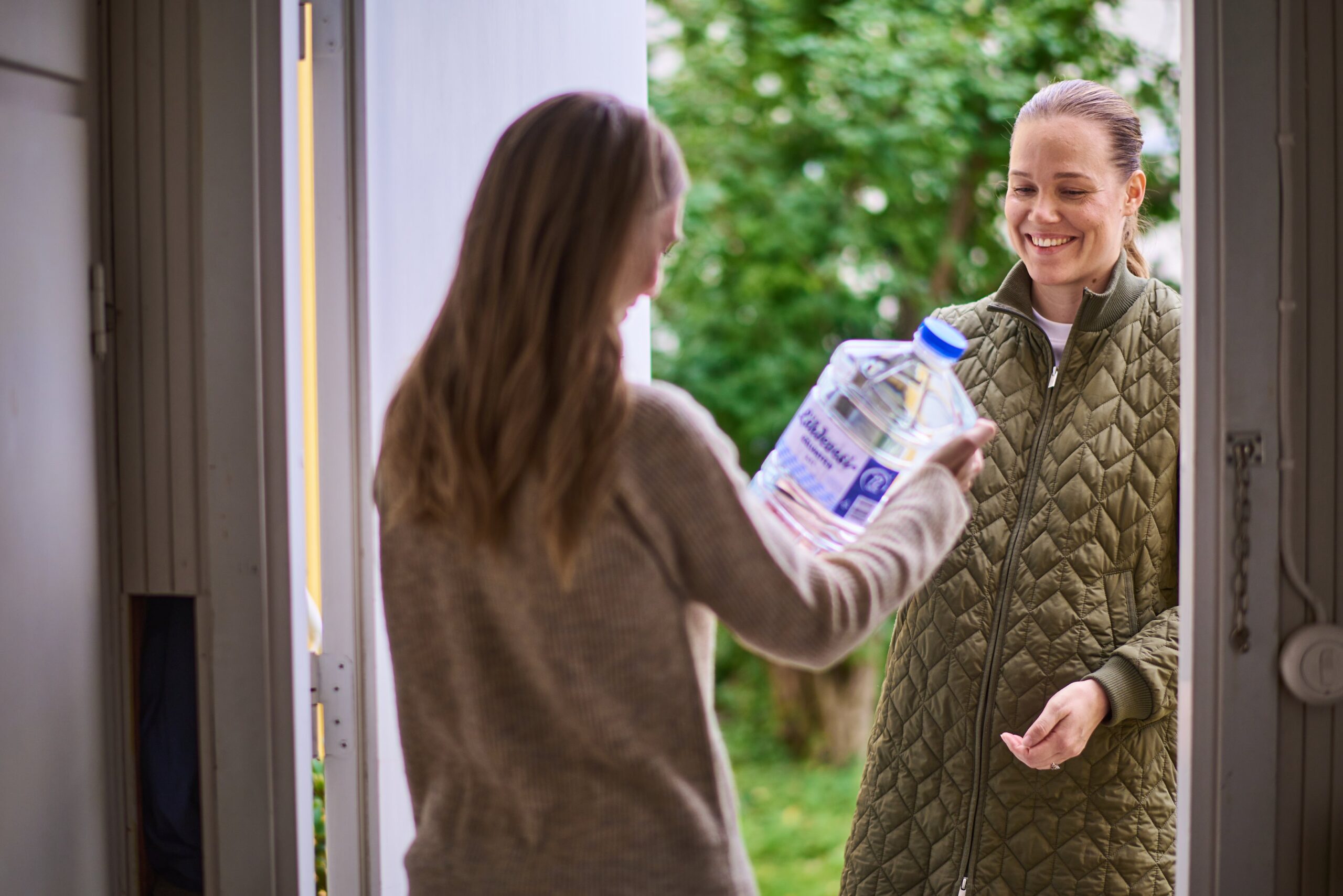 Nainen tuo naapurilleen viiden litran vesitonkan.