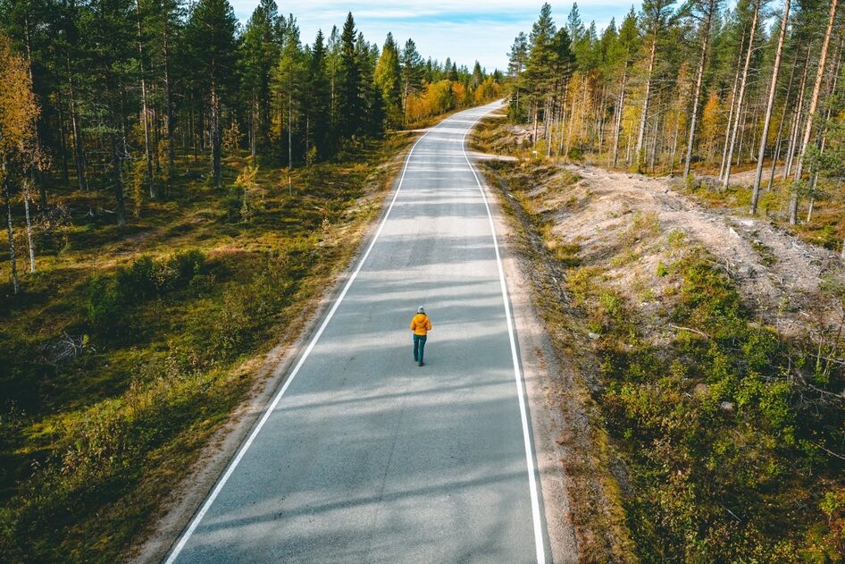 A person stands alone in the middle of a deserted road.