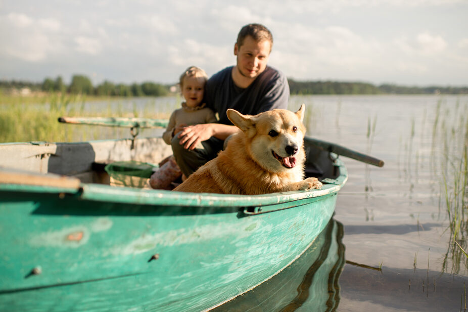 A dog, a man, and a child in a rowboat.