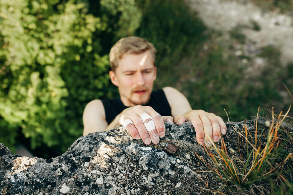 A young man climbing onto a rocky ledge.