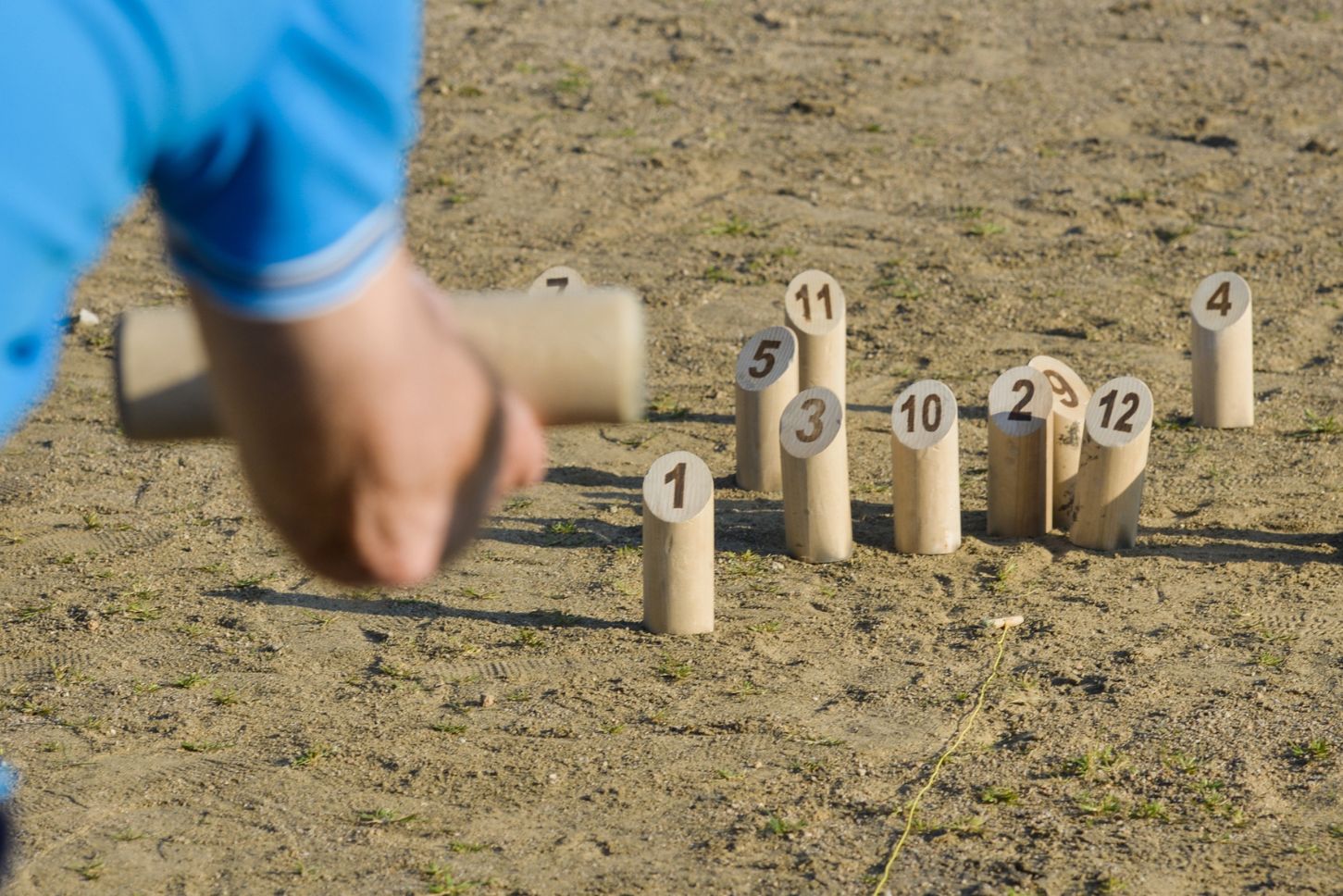 Wooden pins from a Mölkky game on sand.