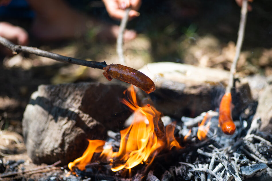 Sausages grilling over an open fire.