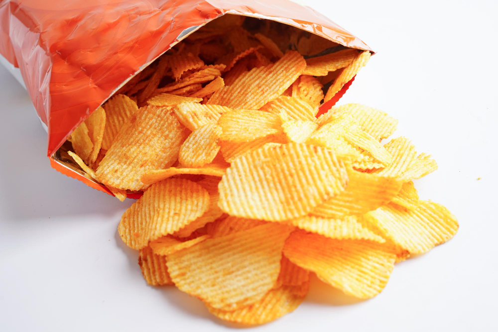 An opened bag of chips and chips on the table.