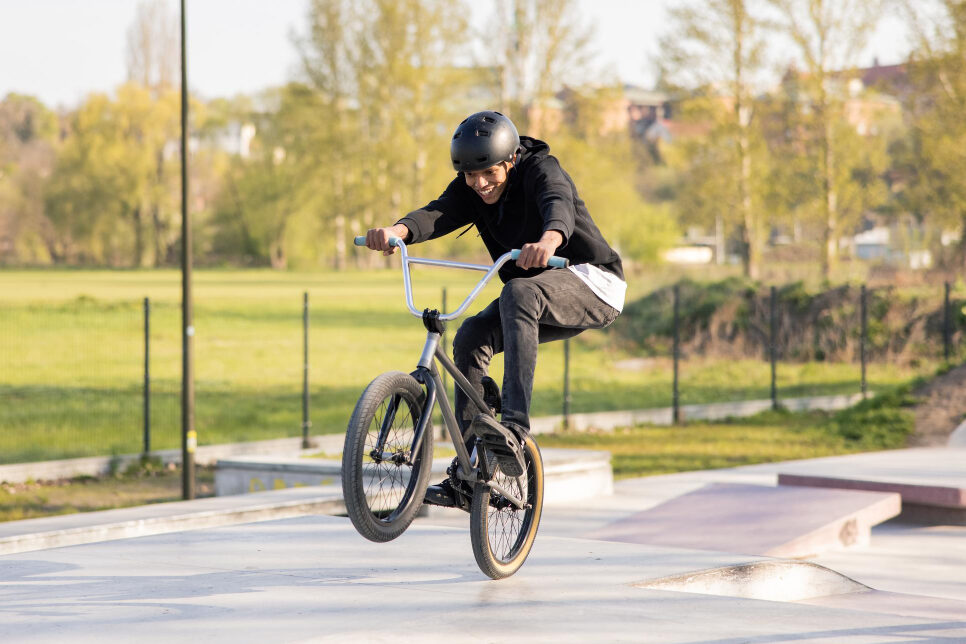 A young person wearing a helmet is riding a BMX bike in a park.