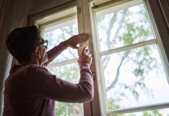 Mies teippaa ikkunankarmeja.
