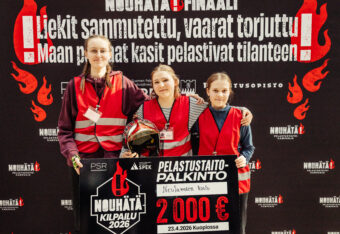 NouHätä-kilpailun voittaneet kolme tyttöä seisovat hymyillen rivissä palkintosekin kanssa.